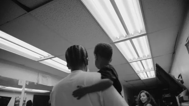 Black-and-white scene from Black Superhero, with a child being held indoors.