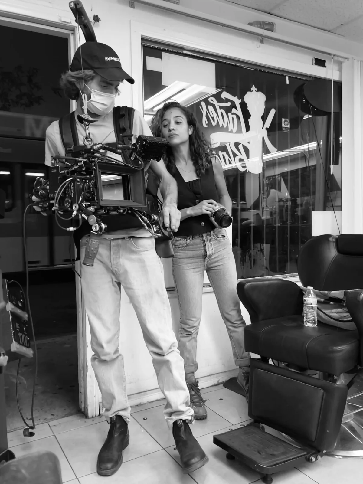 A camera operator and director beside a cinema camera on set.