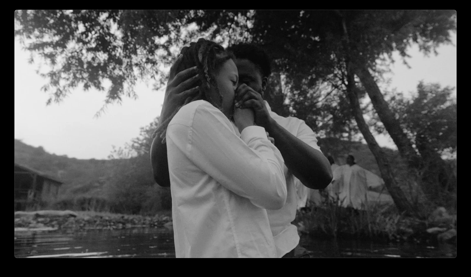 Two people embracing outdoors in a black-and-white scene.