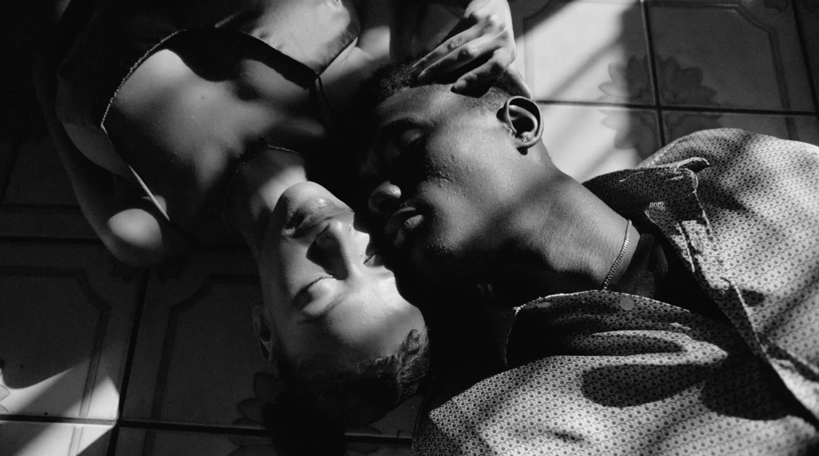 Two people lying head-to-head in a black-and-white close-up.
