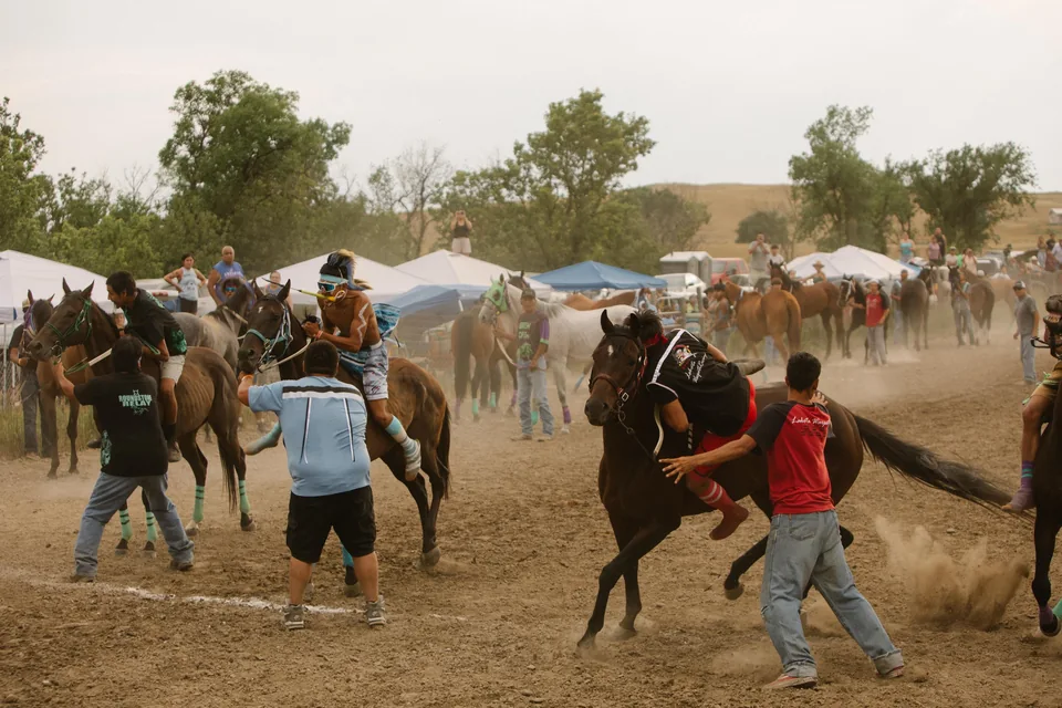 Horse holders guide racing horses through clouds of dust during an exchange.