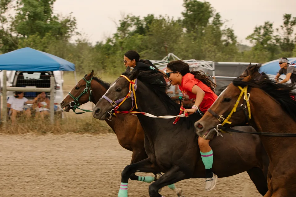 Relay riders in black and red race shoulder to shoulder.