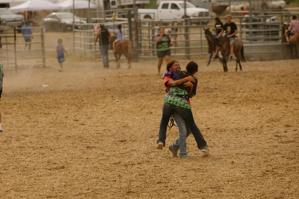 Two people embrace on the dusty track after a race.
