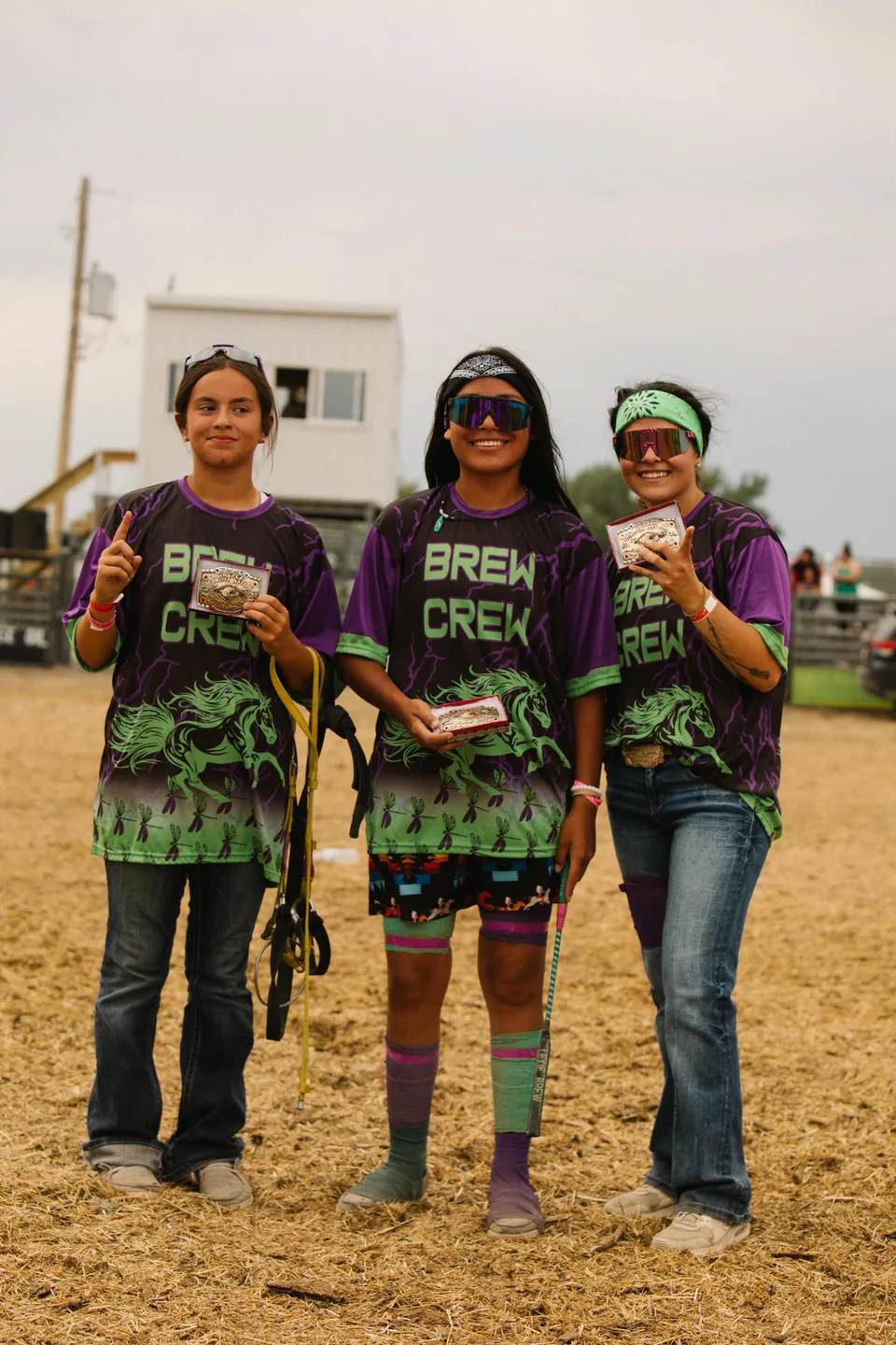 Three Brew Crew team members pose together in matching green and purple shirts.