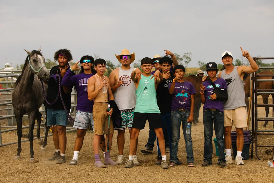 Frontline team members pose together beside a horse at the relay grounds.
