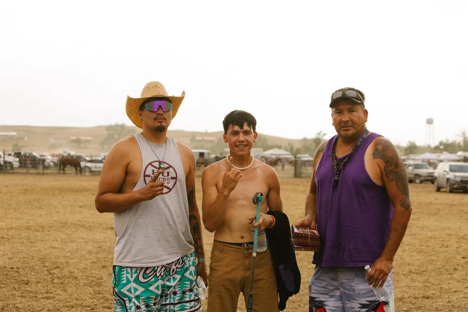 Three team members pose together, one wearing a cowboy hat and purple sunglasses.