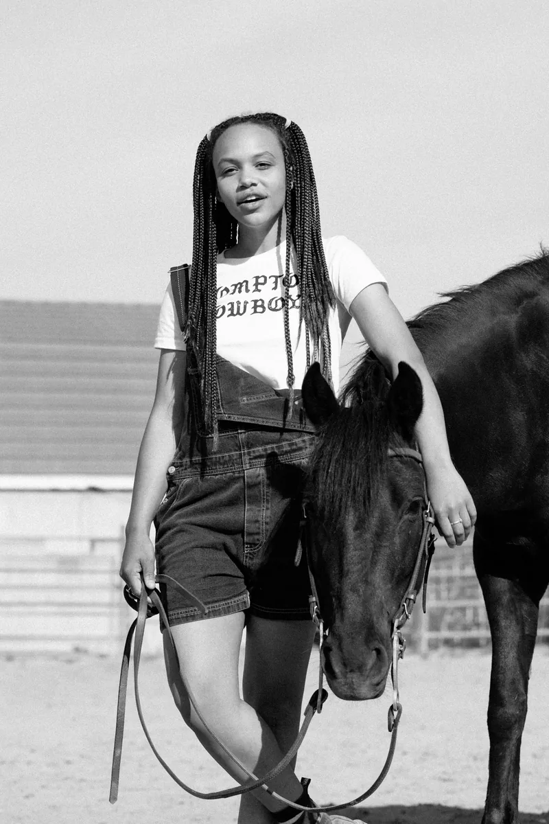 Black-and-white portrait of a woman holding a horse's lead rope.