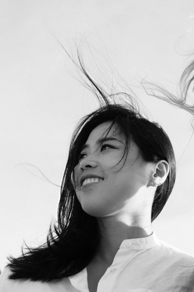 Black-and-white portrait of a smiling woman with windblown hair.