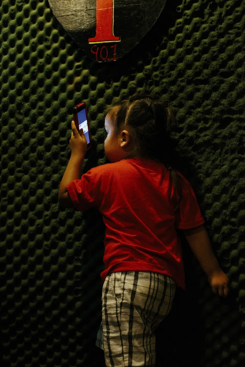 A child in a red shirt playing at an indoor basketball arcade.